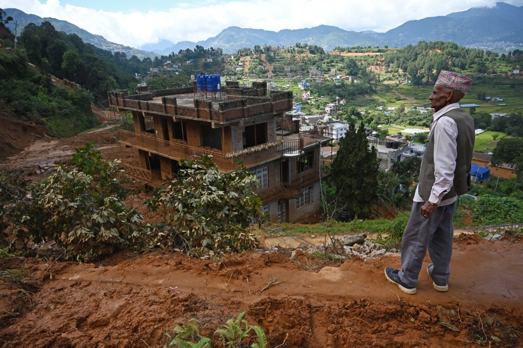 (FILES) A man stands in a landslide-affected village following heavy rains in Lalitpur district on the outskirts of Kathmandu on October 1, 2024.  (Photo by Prakash MATHEMA / AFP)