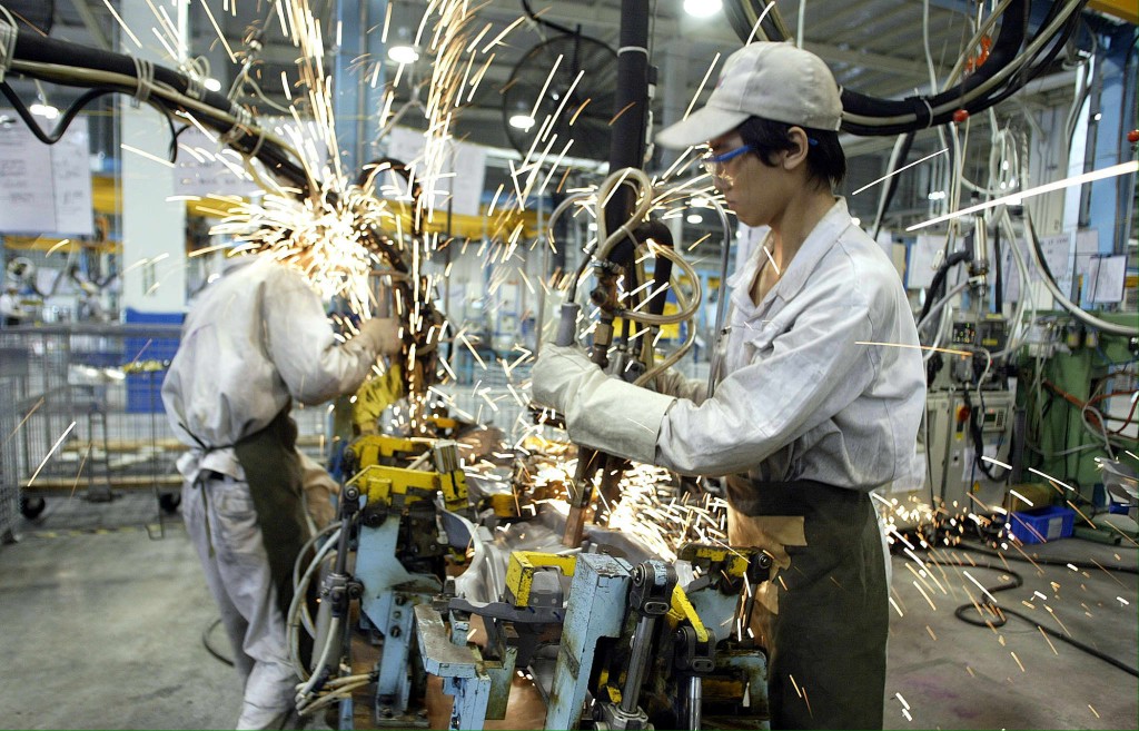 A welder works at the Auto Parts Alliance (China) factory in Guangdong, a Japanese company who supplies parts for Honda, 14 June 2003. AFP