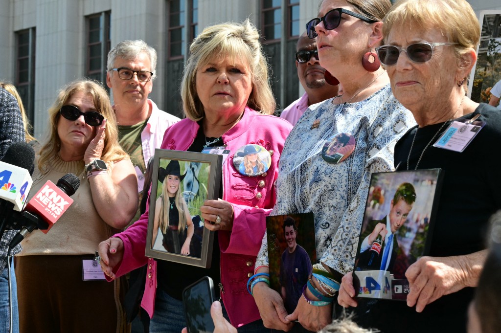 Photo by FREDERIC J. BROWN / AFP Relatives of victims, including Lori Schott (C), stand outside the Los Angeles Superior Court holding portraits of their loved ones in Los Angeles, on March 25, 2026.