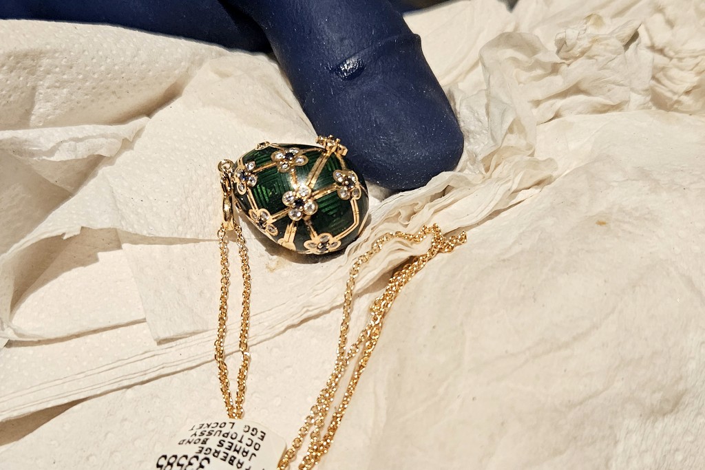 Photo by HANDOUT / NEW ZEALAND POLICE / AFP  This handout photo release by New Zealand Police on December 5, 2025 shows an officer displaying a recovered diamond-encrusted green Fabergé egg in Auckland after keeping a six-day watch over the thief accused of swallowing it.
