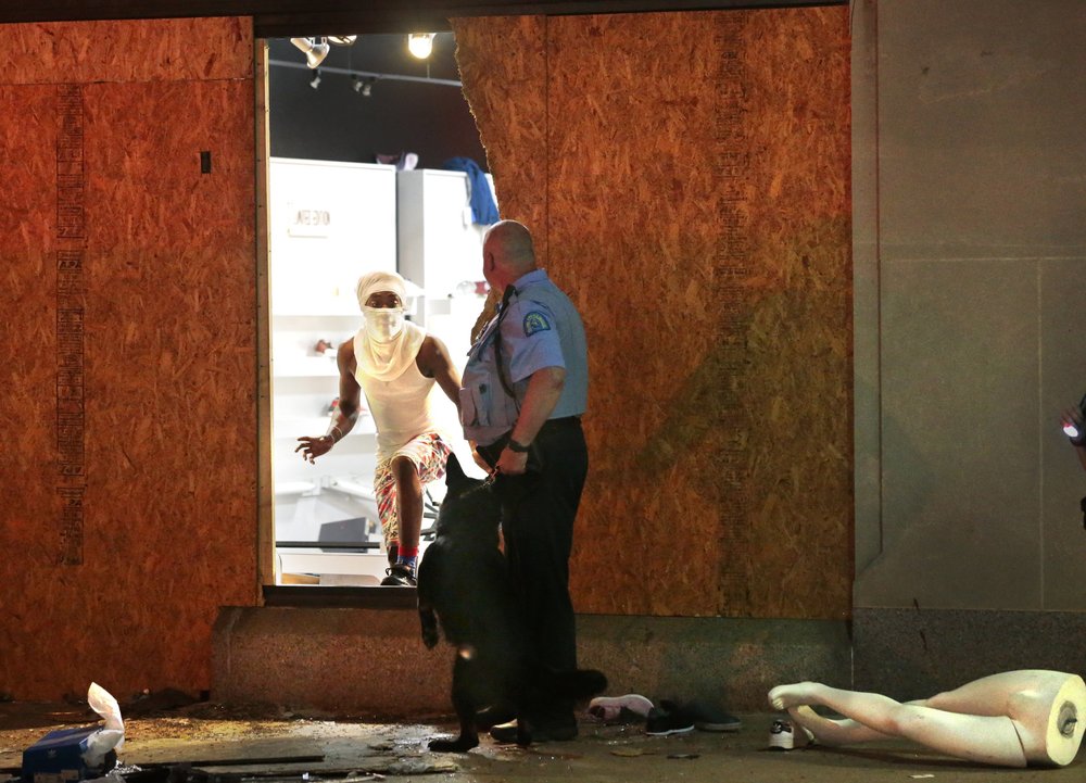 A person about to emerge from a store comes face-to-face with a St. Louis police officer and his K9 at a Fresh Image store Monday night, June 1, in St. Louis. 