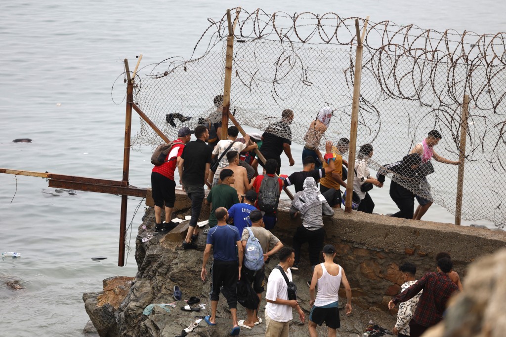 People gather along the fence close to the site of clashes near Fnideq, on the Morocco-Spain border, on July 31, 2026.