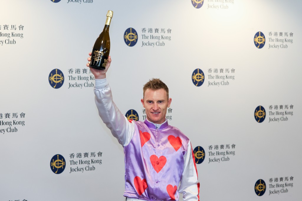 Zac Purton raises a celebratory bottle of champagne in honor of his 1,900th Hong Kong winner (HKJC) 