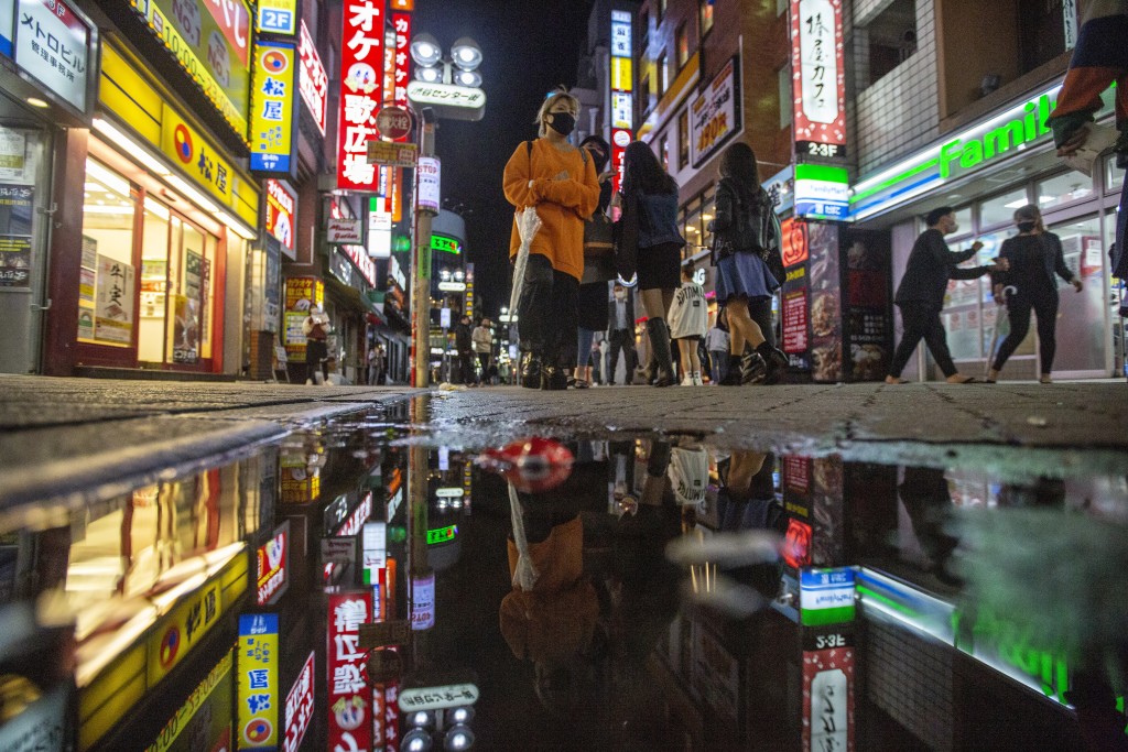 People walk along the streets full of shops, bars and restaurants Friday night, Oct. 1, 2021, in Shibuya, an entertainment district of Tokyo, as Japan fully came out of a coronavirus state of emergency for the first time in more than six months. Japan is poised to approve a record 56 trillion yen, or $490 billion stimulus package, including cash handouts and aid to ailing businesses, to help the economy out of the doldrums worsened by the coronavirus pandemic.(AP Photo/Kiichiro Sato)