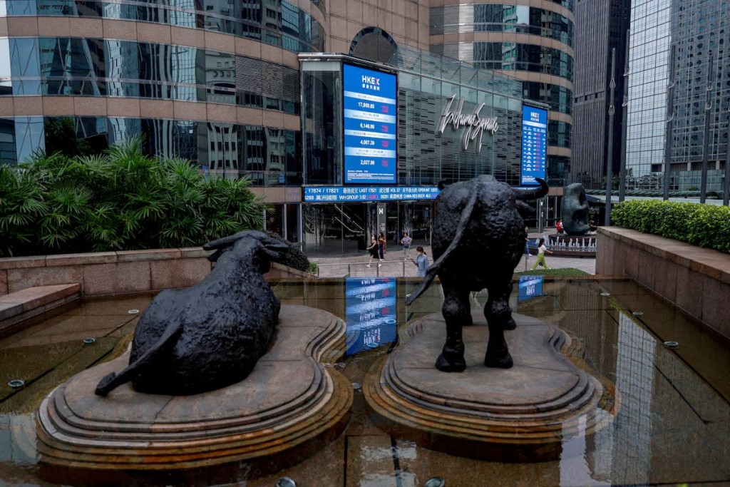 Bull statues stand in font of screens showing the Hang Seng stock index and stock prices outside Exchange Square in Hong Kong, China, August 18, 2023. REUTERS