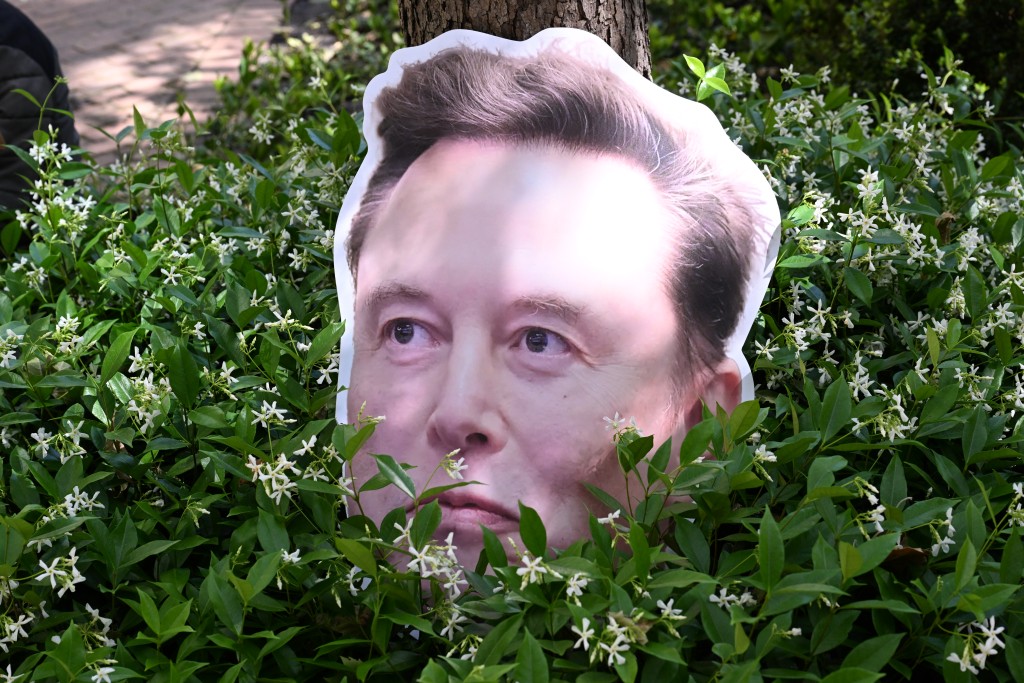 Photo by JOSH EDELSON / AFP  An Elon Musk sign sits in a bush the federal courthouse during proceedings in the trial over Elon Musk's lawsuit against OpenAI in Oakland, California, on April 30, 2026.