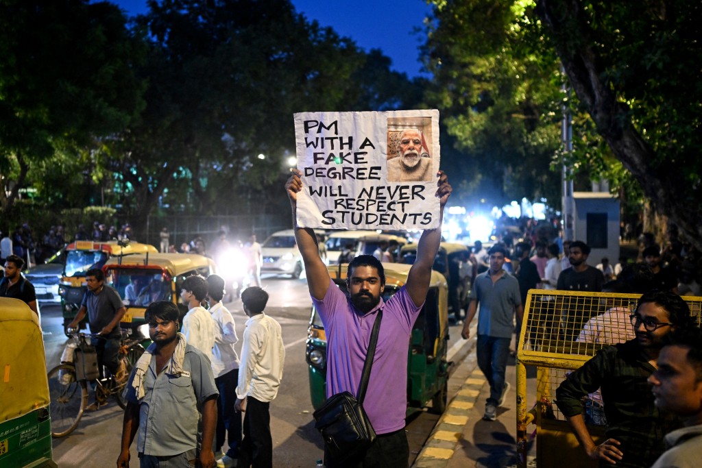 Photo by SAJJAD HUSSAIN / AFP  A Cockroach Janta Party (CJP) supporter holds a placard at Connaught Place in New Delhi on July 24, 2026 in solidarity with the ongoing protest at Jantar Mantar demanding the resignation of the country's Education Minister Dharmendra Pradhan over alleged NEET examination irregularities.
