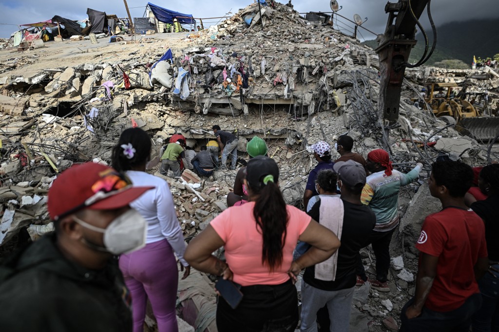 People search for bodies amid the rubble of a building in Caraballeda, Venezuela, on July 22, 2026, nearly a month after the June 24 earthquakes. The number of people killed in the powerful dual Venezuela earthquakes last month rose to 5,278, according to official figures updated on July 20, 2026.