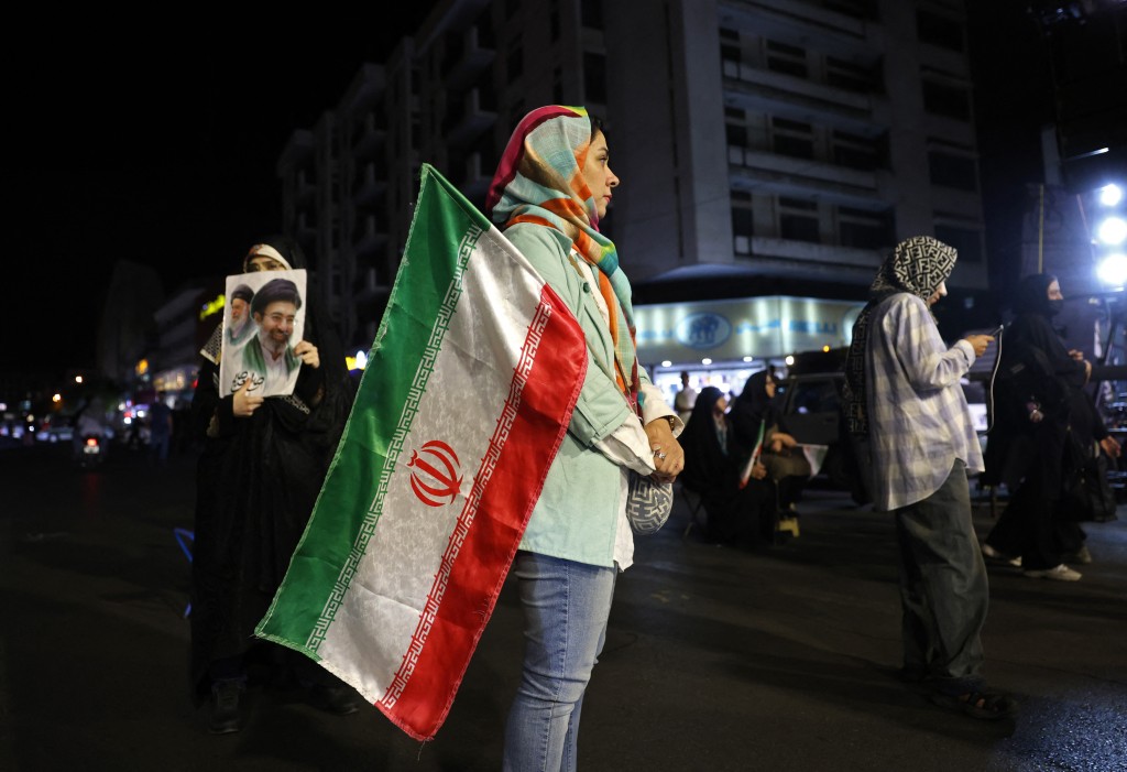 Photo by - / AFP  Women hold Iran's national flag and photos of country's supreme leader Ayatollah Mojtaba Khamenei and his predecessor and late father Ayatollah Ali Khamenei during an anti-US and Israel protest at the Hafte Tir Square in Tehran on May 17, 2026.