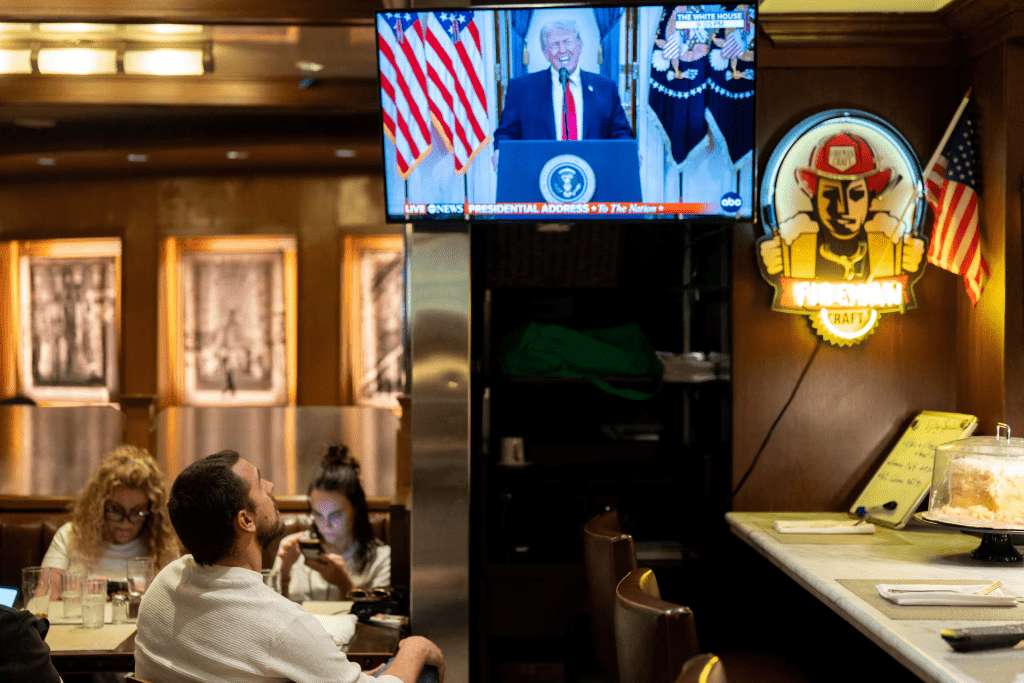 A customer watches U.S. President Donald Trump address the nation on the Iran crisis from the White House in Washington, D.C., on screen at Brooklyn Diner in Times Square, New York, U.S., April 1, 2026. REUTERS/David Dee Delgado