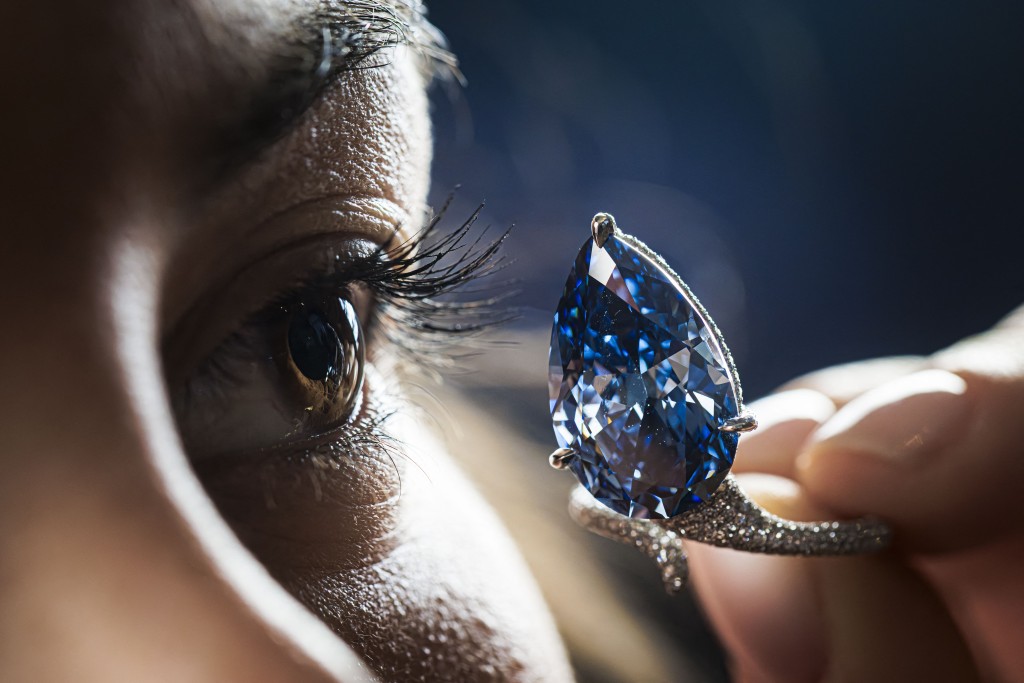 Photo by VALENTIN FLAURAUD / AFP  A staff member shows a 9.51-carat vivid blue diamond, known as "The Mellon Blue", during its presentation at Christie’s auction house in Geneva on November 7, 2025.