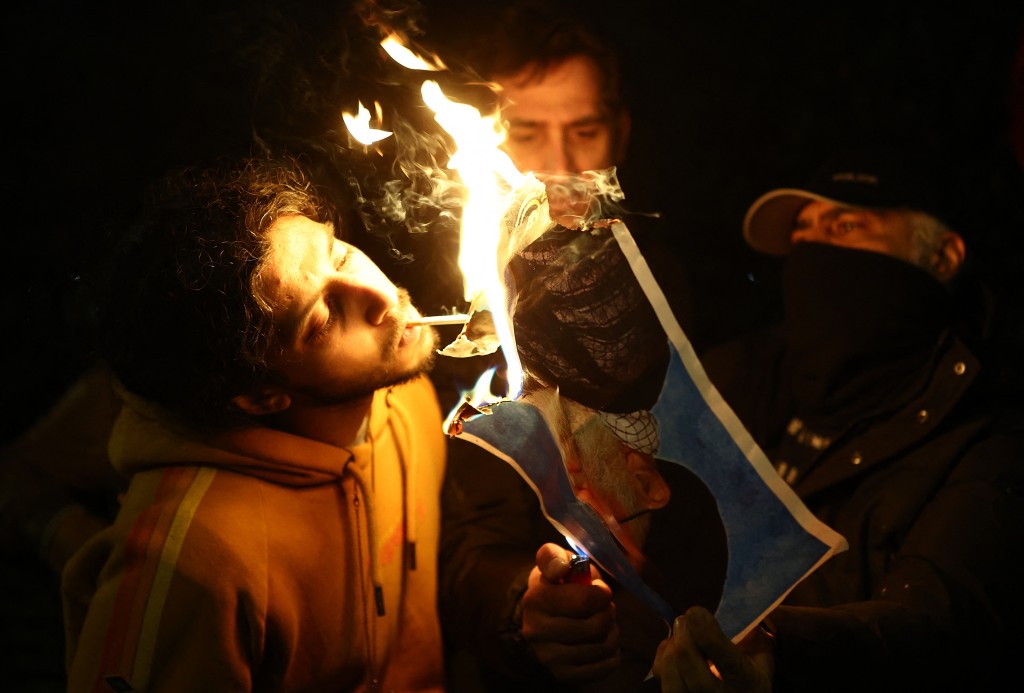 Anti-Iranian regime protesters burn an image of Ayatollah Ali Khamenei, during a gathering outside the Iranian Embassy, central London, on January 12, 2026. (Photo by Henry NICHOLLS / AFP)