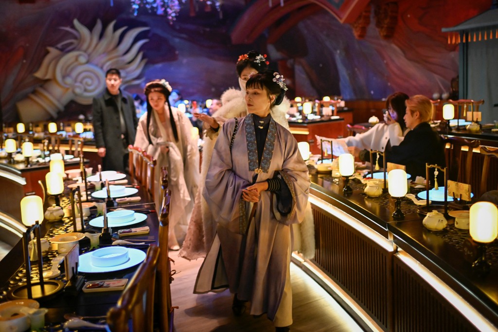 Photo by WANG ZHAO / AFP  This picture taken on November 5, 2025 shows a woman wearing traditional Chinese clothes arriving for a meal at a theatrical restaurant in Beijing.