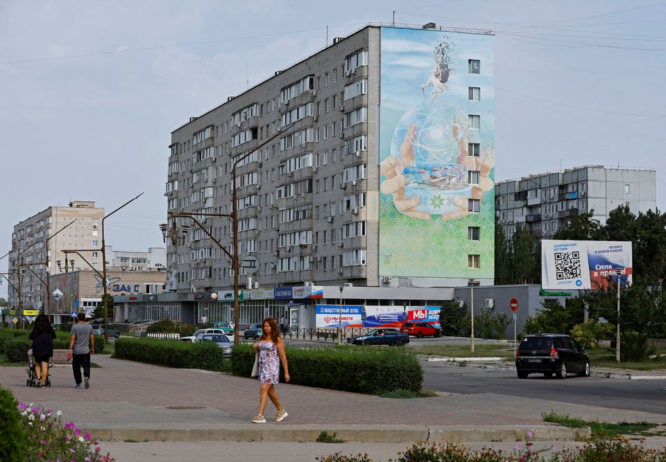People walk along a street in the course of Ukraine-Russia conflict in the Russian-controlled city of Enerhodar in Zaporizhzhia region, Ukraine. (Reuters) People walk along a street in the course of Ukraine-Russia conflict in the Russian-controlled city of Enerhodar in Zaporizhzhia region, Ukraine. (Reuters)