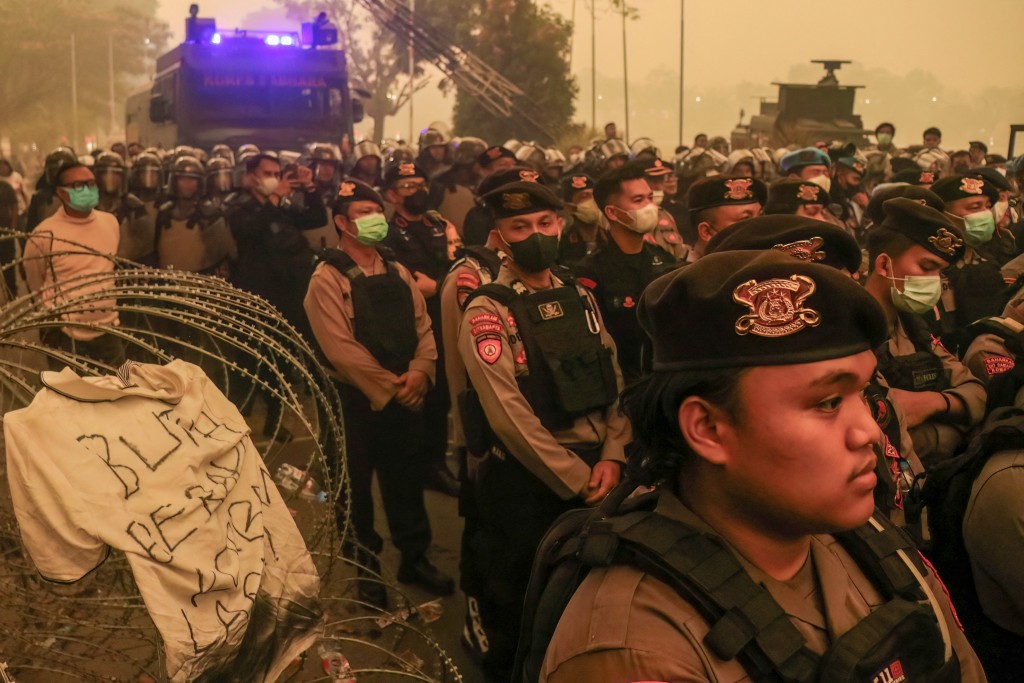 Riot police officers stand guard behind barbed wire as demonstrators gather outside the Central Kalimantan Governor's office during a protest over forest and land fires in Palangkaraya on October 23, 2026. (Photo by REINA / AFP)