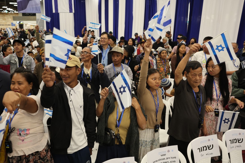 Photo by JACK GUEZ / AFP  Members of the Bnei Menashe (Sons of Manasseh) community from India wave Israeli flags as they arrive at Ben Gurion Airport in Lod, near Tel Aviv, on April 23, 2026.