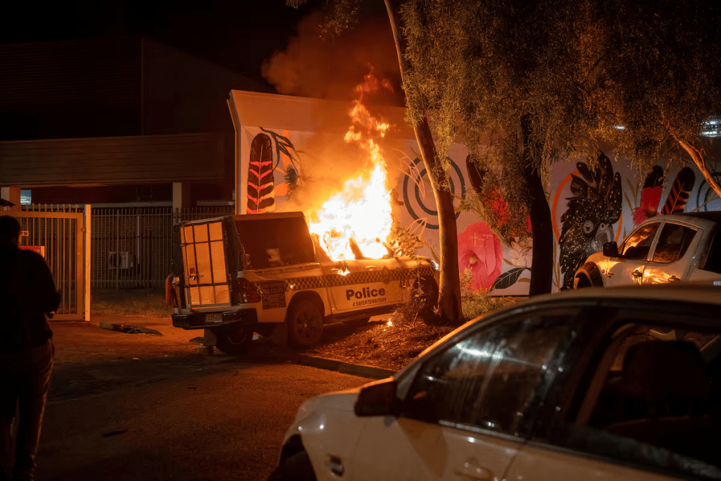 A police vehicle burns after community members clashed with police outside Alice Springs Hospital, where a 47-year-old man arrested in connection with the alleged killing of five-year-old Kumanjayi Little Baby was taken, in Alice Springs, Australia, April 30, 2026. Rhett Hammerton/AAP/via REUTERS 
