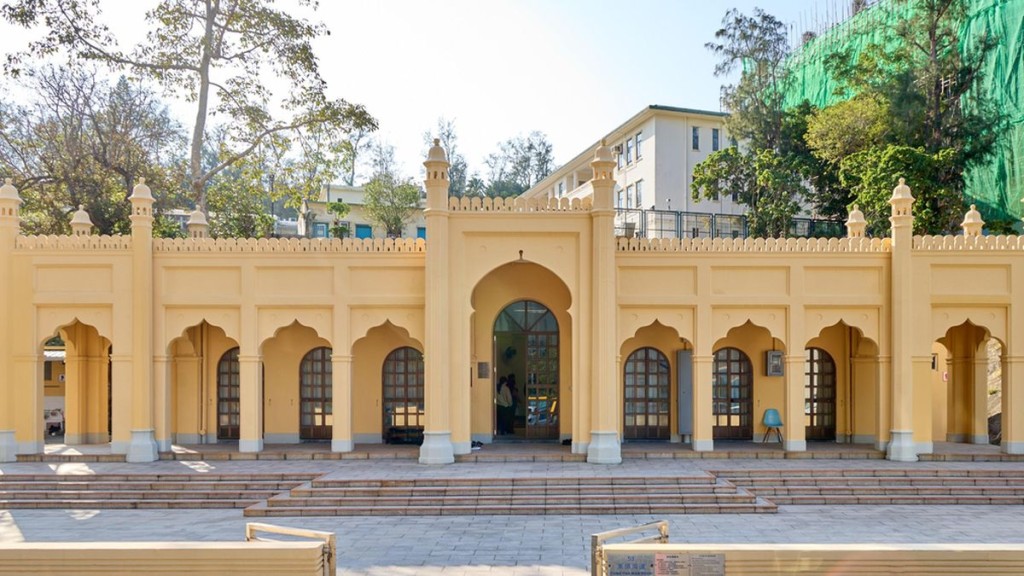 Photo shows the minaret-like columns and crenellated parapet surrounding the flat roof of the mosque.