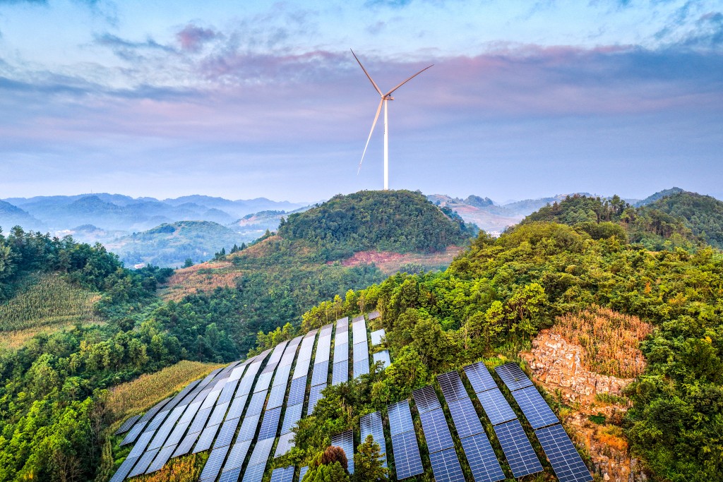 Solar panels are arranged on a hillside near a windmill at an agricultural photovoltaic power station in Dingxin Yi and Miao Ethnic Township, Qianxi City, in southwestern China's Guizhou province, on August 17, 2026. (Photo by CN-STR / AFP) / CHINA OUT