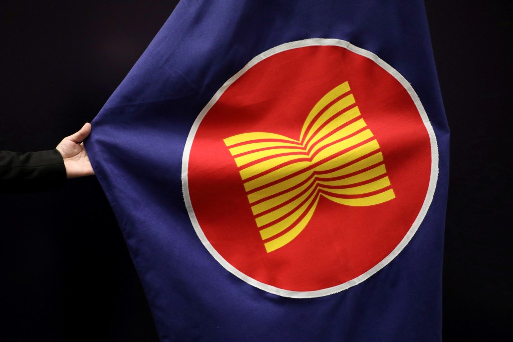 A worker adjusts an ASEAN flag at a meeting hall in Kuala Lumpur, Malaysia, October 28, 2021. REUTERS/Lim Huey Teng/File Photo