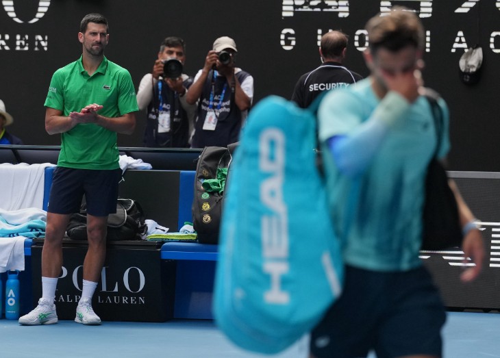 Novak Djokovic applauds Lorenzo Musetti as the Italian departs Rod Laver Arena with an injury after taking the first two sets of their quarter-final. AP