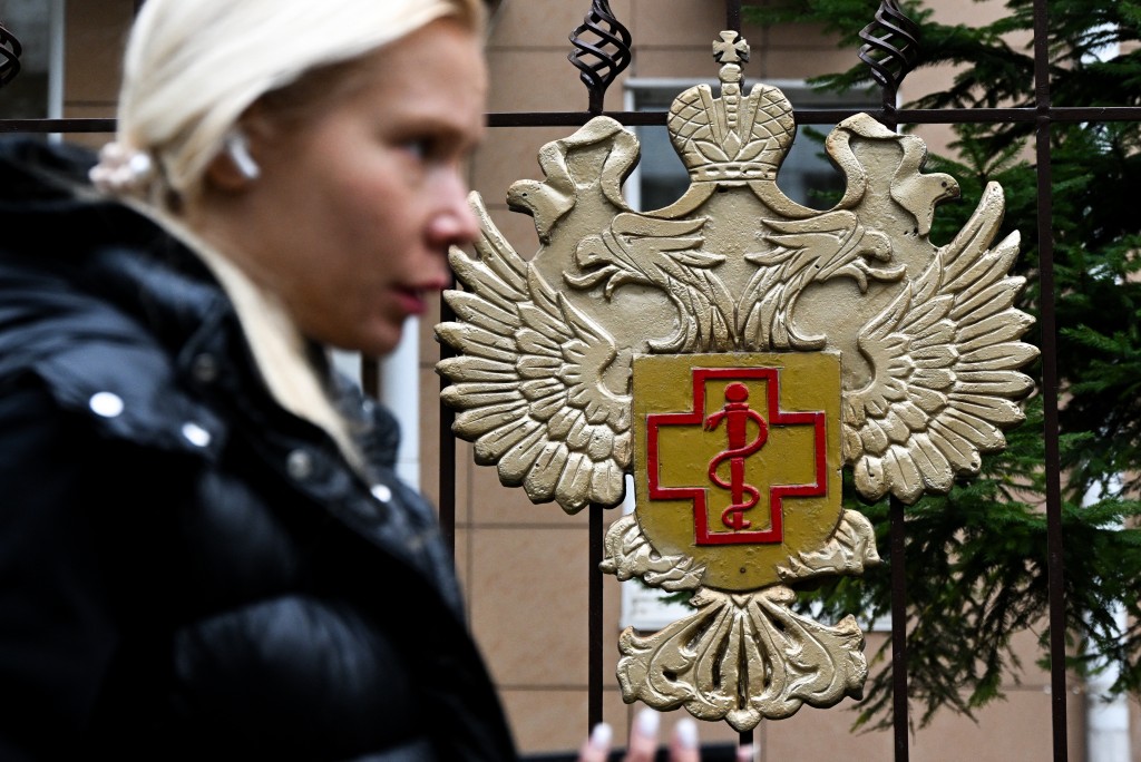 Photo by IGOR IVANKO / AFP  A woman walks past the logo of Russia's consumer and health watchdog Rospotrebnadzor sitting on its grounds' fencing in Moscow on October 5, 2026.