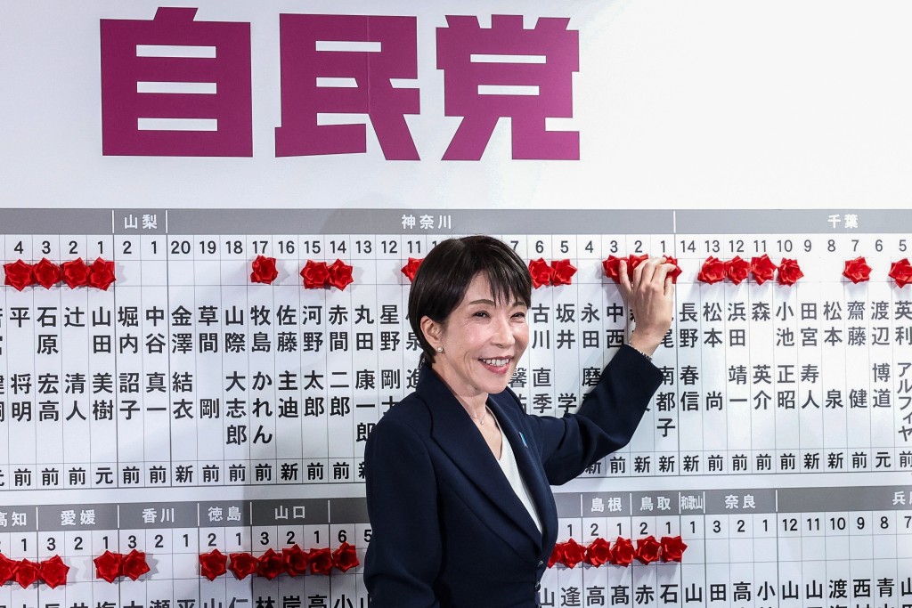 Japan's Prime Minister and President of the Liberal Democratic Party (LDP) Sanae Takaichi places a red paper rose on the name of an elected candidate at the LDP headquarters during the House of Representatives election in Tokyo on February 8, 2026. (AFP)