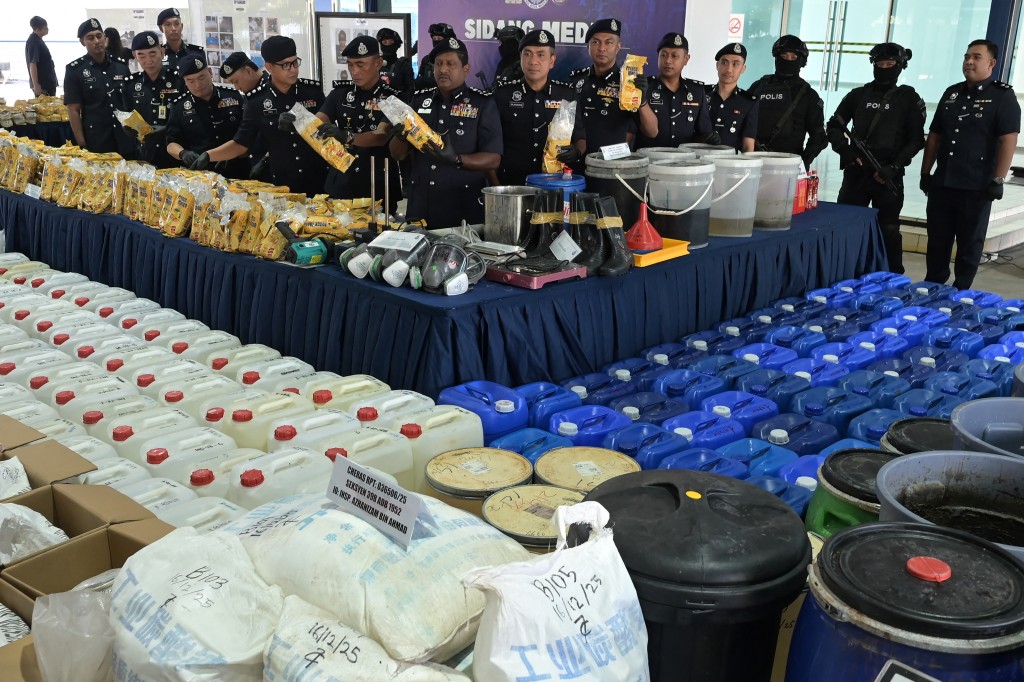Photo by STR / AFP. Members of the Royal Malaysia Police display seized illegal drugs and drug-making equipment during a press conference in Kuala Lumpur on December 20, 2025.