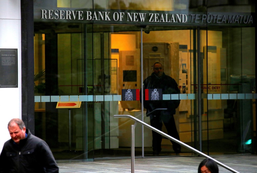 Pedestrians walk past as a security guard stands in the main entrance to the Reserve Bank of New Zealand located in central Wellington, New Zealand, July 3, 2017. Reuters