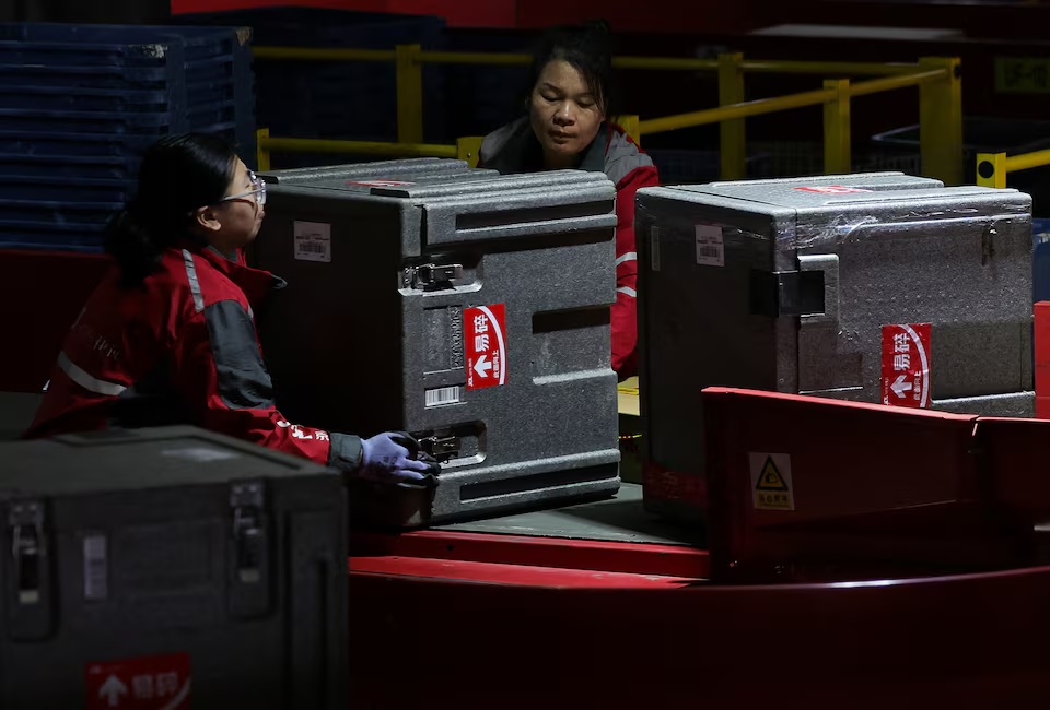 Employees turn a transportation parcel box moving on the conveyor belt at the JD.com sorting center in Beijing, China, November 11, 2025. REUTERS/Maxim Shemetov