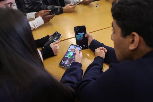 Students from Ricards Lodge and Rutlish High Schools in Wimbledon look at their mobile phones during an interview and discussion with Reuters about their thoughts on a social media ban for under 16s, in London, Britain, February 23, 2026, REUTERS/Katie Collins