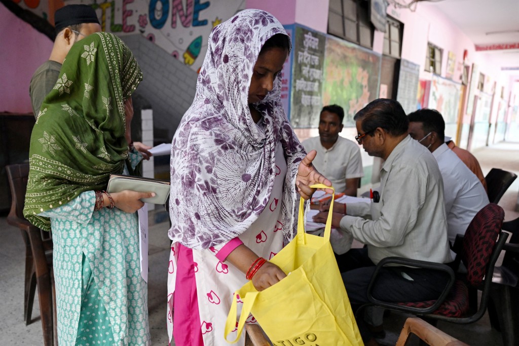 Photo by ARUN SANKAR / AFP  Laddli Khatun (C), a slum dweller searches her bag for documents to register for the Draft Electoral Roll 2026 as part of the Election Commission of India's Special Intensive Revision (SIR), at a voter verification camp in New Delhi on October 18, 2026.