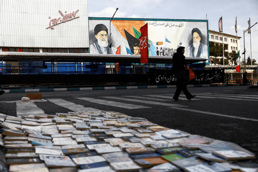 A woman walks next to a mural depicting the late leader of the Islamic Revolution, Ayatollah Ruhollah Khomeini, and the late Supreme Leader of Iran, Ayatollah Ali Khamenei, amid the U.S.-Israeli conflict with Iran, in Tehran, Iran, March 22, 2026. Majid Asgaripour/WANA (West Asia News Agency) via REUTERS/File Photo
