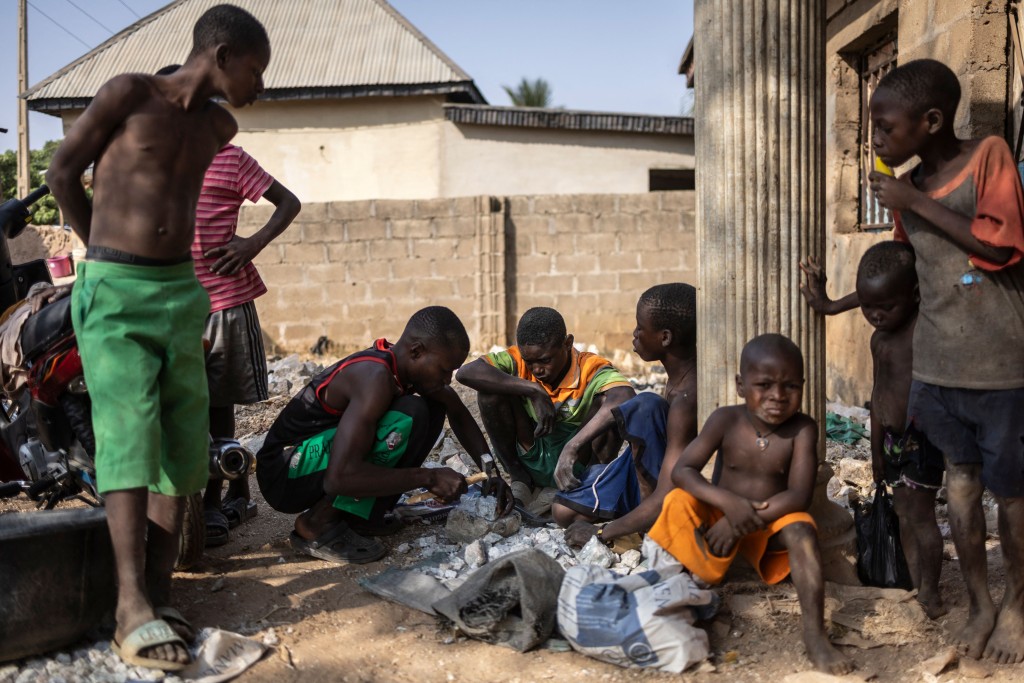 Children break stones that contain lithium at a warehouse in Nasarawa, in Nasarawa state, on January 23, 2025. In a day's work, a worker fills three bags of 50 kg each, which earns him 150,000 naira ($100), twice the minimum monthly wage in Nigeria, the most populous country in Africa where more than half the population lives below the poverty line. According to the International Energy Agency (IEA), global demand for lithium will increase forty-fold by 2040, a growth that cannot be met by the current main
