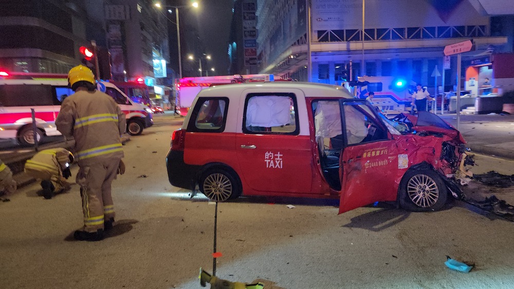 Both the taxi and motorcycle are a wreck following the collision. Medics treat one of the injured while a sidewalk fencing is bent after it was hit by the taxi. SING TAO Both the taxi and motorcycle are a wreck following the collision. Medics treat one of the injured while a sidewalk fencing is bent after it was hit by the taxi. SING TAO