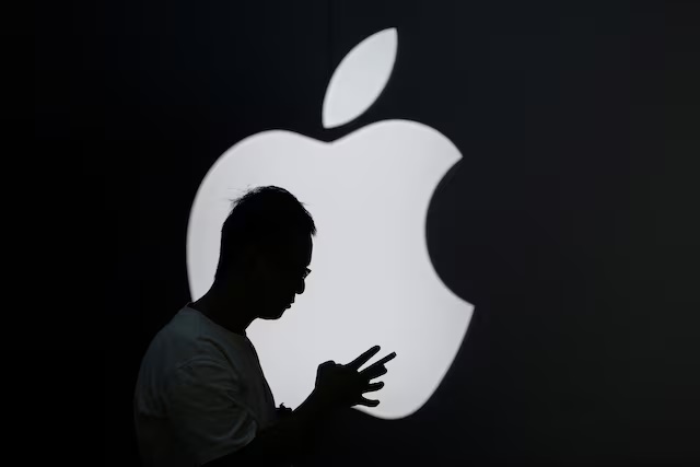 A man check his phone near an Apple logo outside its store in Shanghai, China September 13, 2023. REUTERS/Aly Song
