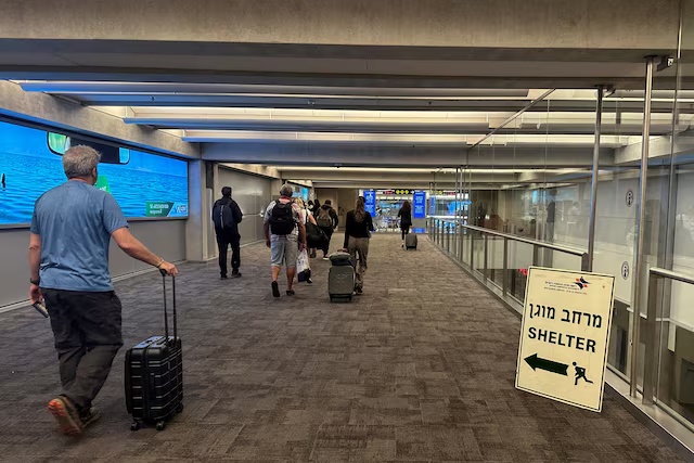 People walk next to a sign directing for Shelter after landing in Israel at the arrivals section of Ben Gurion International airport in Lod near Tel Aviv, Israel October 11, 2023 REUTERS/Marius Bosch/File Photo