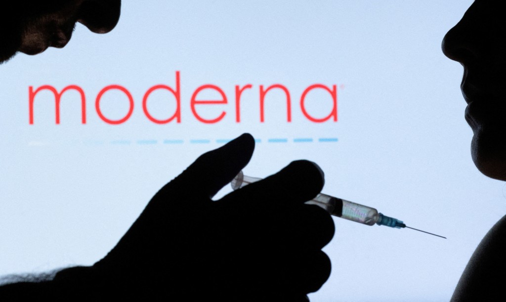 People pose with syringe with needle in front of displayed Moderna logo in this illustration taken, December 11, 2021. REUTERS