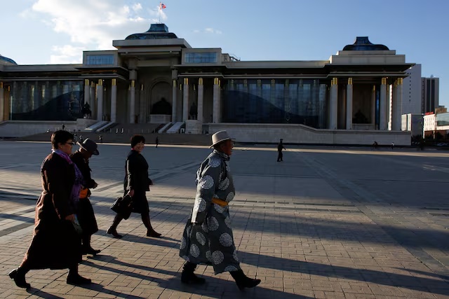 People in traditional clothes walk past the parliament building in Sukhbaatar square in Ulaanbaatar, Mongolia, April 30, 2018. REUTERS/Thomas Peter