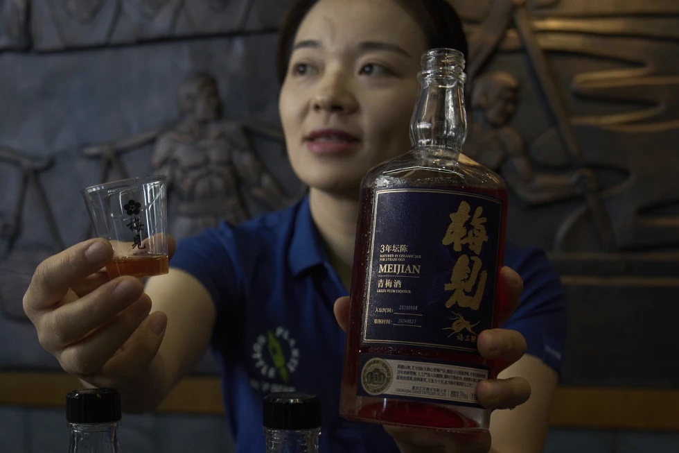 A worker shows the Green Plum Liqueur, a mix handcrafted single sorghum baijiu with plum juice to reporters during a media organized tour at Jiangxiaobai Liquor Co.'s Jiangji Distillery in southwestern China’s Chongqing on May 19, 2025. (AP Photo/Andy Wong)