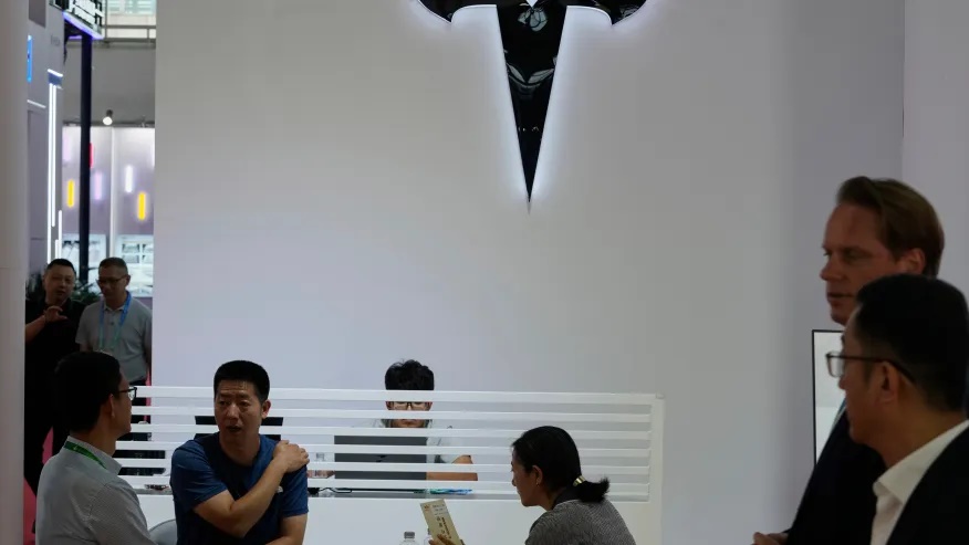 Visitors at the Tesla booth during the 3rd China International Supply Chain Expo at the China International Exhibition Center, in Beijing, China, Friday, July 18, 2025. (AP Photo/Mahesh Kumar A.)