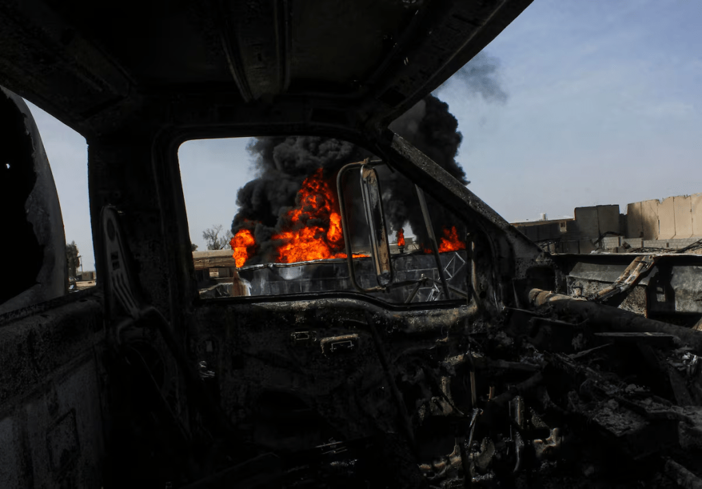 Thick black smoke is seen through a destroyed truck at the private airline Kam Air's fuel depot after a strike in what the Taliban said was a Pakistani air strike, in Kandahar, Afghanistan, March 13, 2026. REUTERS/Stringer