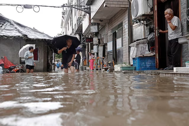Residents wade through floodwaters at a flooded residential compound amid heavy rainfall brought by Typhoon Dolphin, in Shanghai, China August 10, 2026. cnsphoto via REUTERS