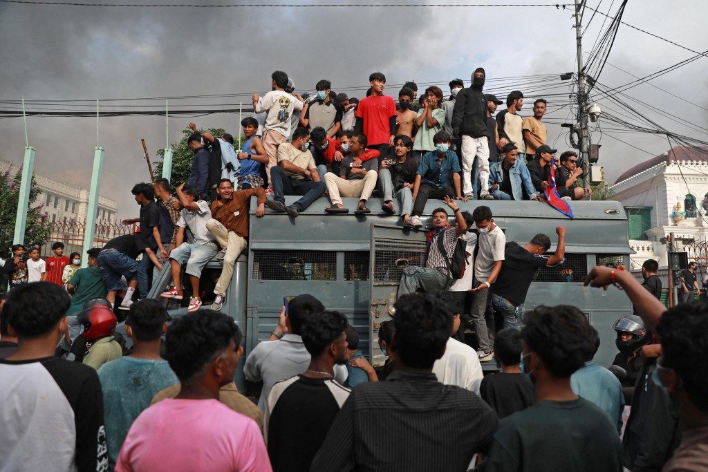 Protesters gather on a security vehicle outside the Singha Durbar, the main administrative building of the Nepal government, in Kathmandu on September 9, 2025. (AFP)