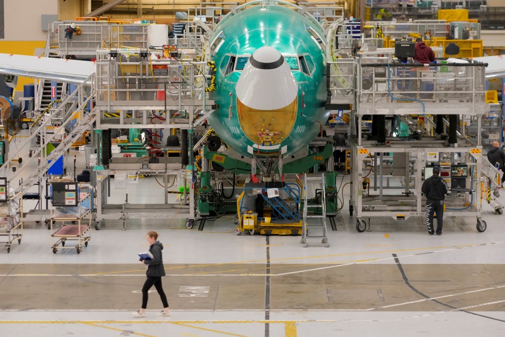 A Boeing worker passes by a 737 MAX airplane on the final assembly production line during a media tour of the Boeing factory in Renton, Washington, U.S., April 15, 2026.
