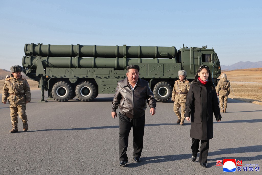 This picture taken on January 27, 2026 and released by North Korea's official Korean Central News Agency (KCNA) on January 28, 2026 shows North Korean leader Kim Jong Un (C) and his daughter Kim Ju Ae (R) inspecting a test firing of the renewed large-caliber rocket launcher system, at an undisclosed location in North Korea. (Photo by KCNA VIA KNS / AFP)
