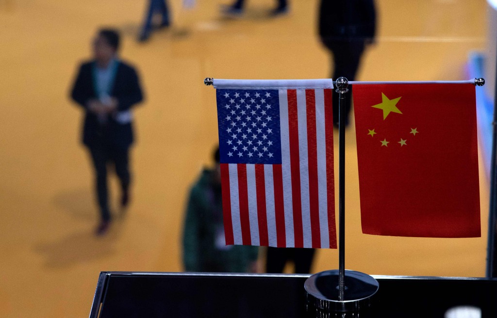This picture taken on November 6, 2018 shows a Chinese and US flag at a booth during the first China International Import Expo (CIIE) in Shanghai. - There is a notable absentee among the dozens of national pavilions at a massive Chinese import fair -- the United States -- a no-show that underlines how Trump economic policies are causing trading partners to turn more toward China. (Photo by Johannes EISELE / AFP)