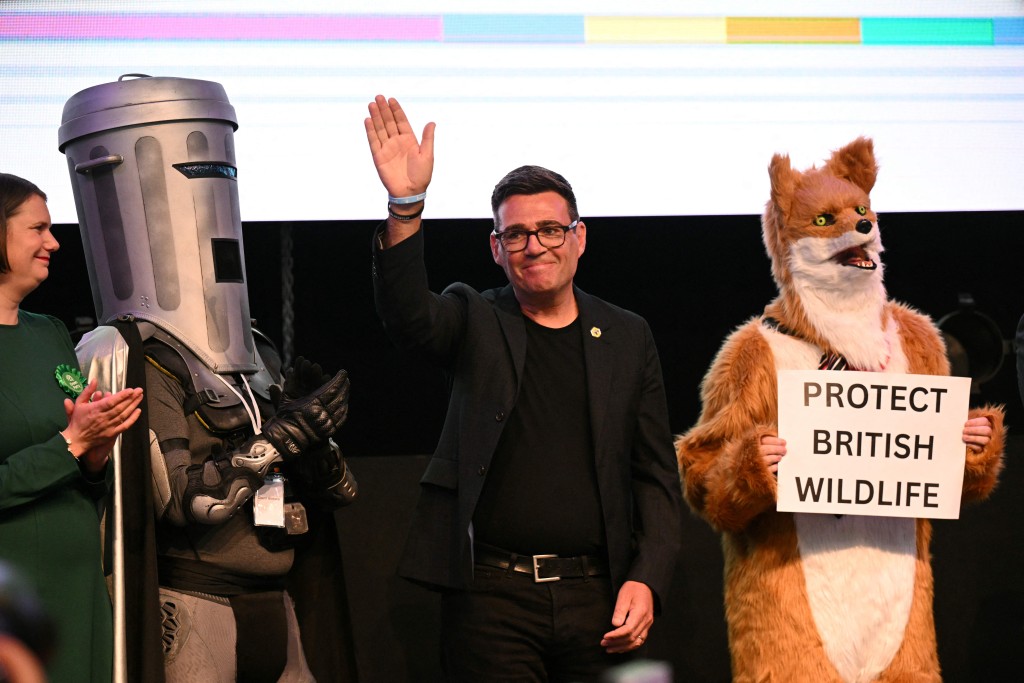 Photo by OLI SCARFF / AFP  Labour candidate Andy Burnham (C) waves to the crowd after he won the election for MP of Makerfield, at the count centre venue in Wigan, northwest England on June 19, 2026.