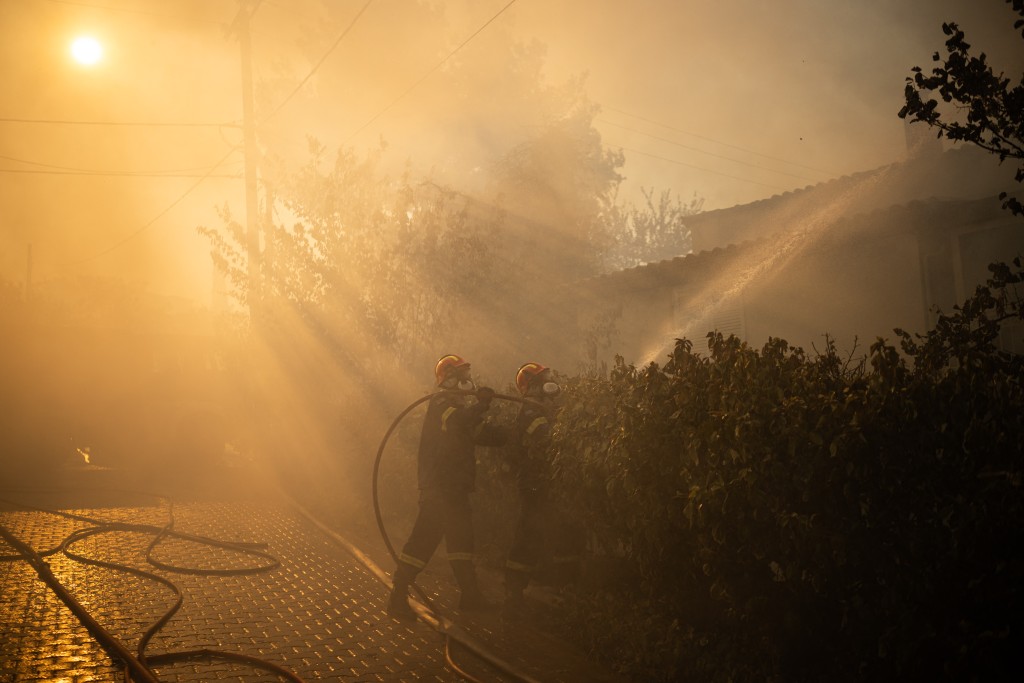 Firefighters try to extinguish the fire of a burning house during a wildfire in Kryoneri, near Athens on July 26, 2025. (AFP)