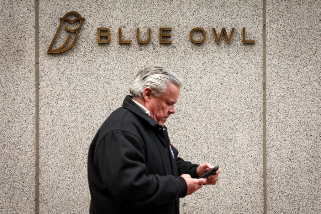 A man walks past a logo for Blue Owl Capital on a midtown Manhattan office building in New York City, U.S., February 24, 2026.  REUTERS
